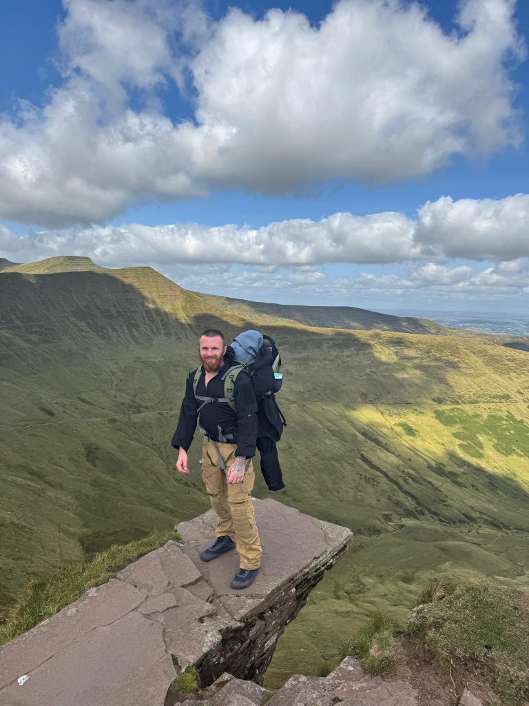 Hiker standing on scenic mountain cliff edge.